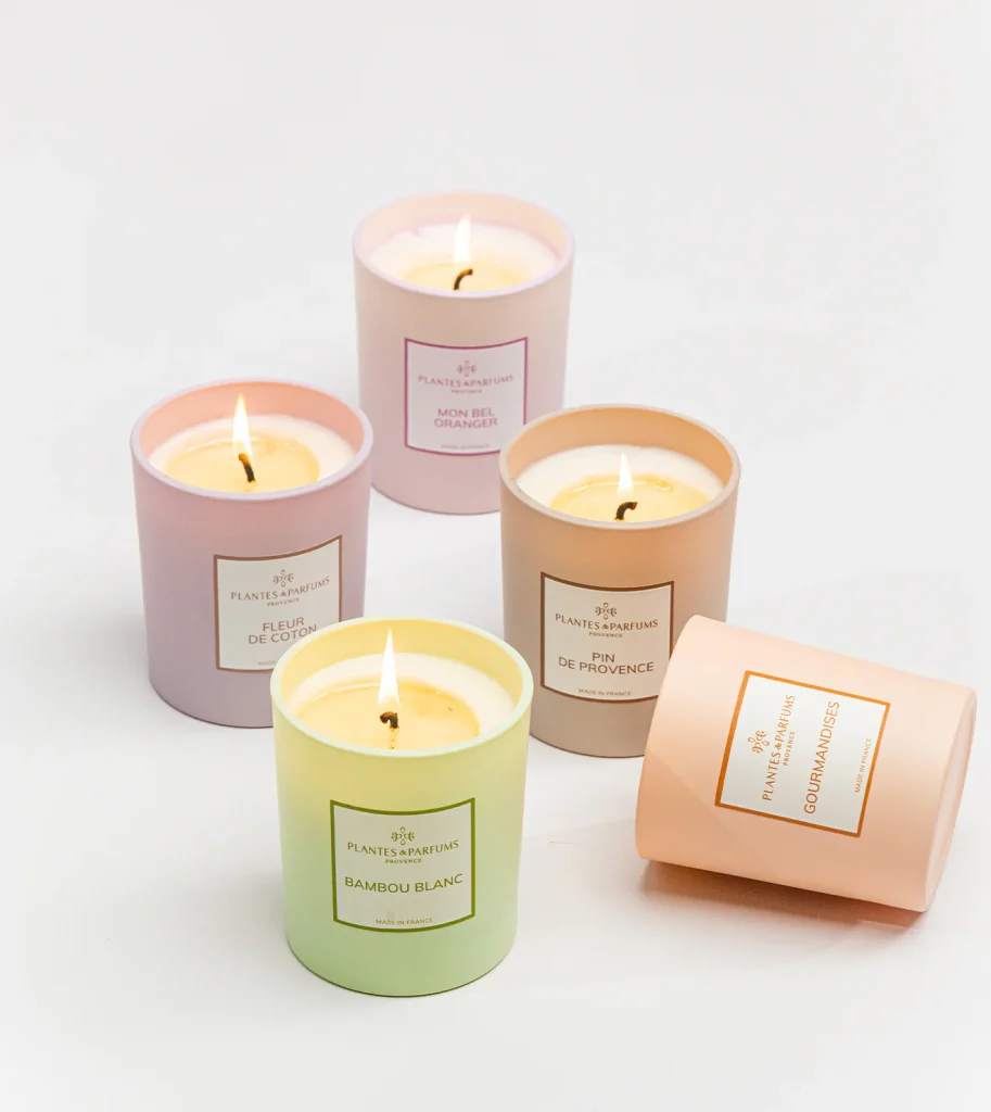 5 bougies dont 4 allumées et 1 renversée. Une verte, une violette, une rose, une marron et une rose.